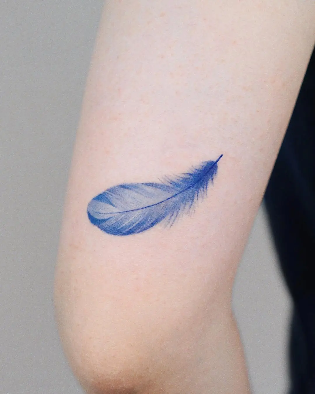 Elegant blue feather tattoo on the arm