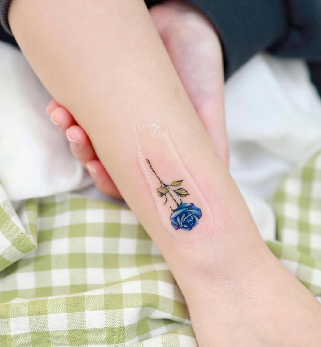 Delicate blue rose tattoo on an arm