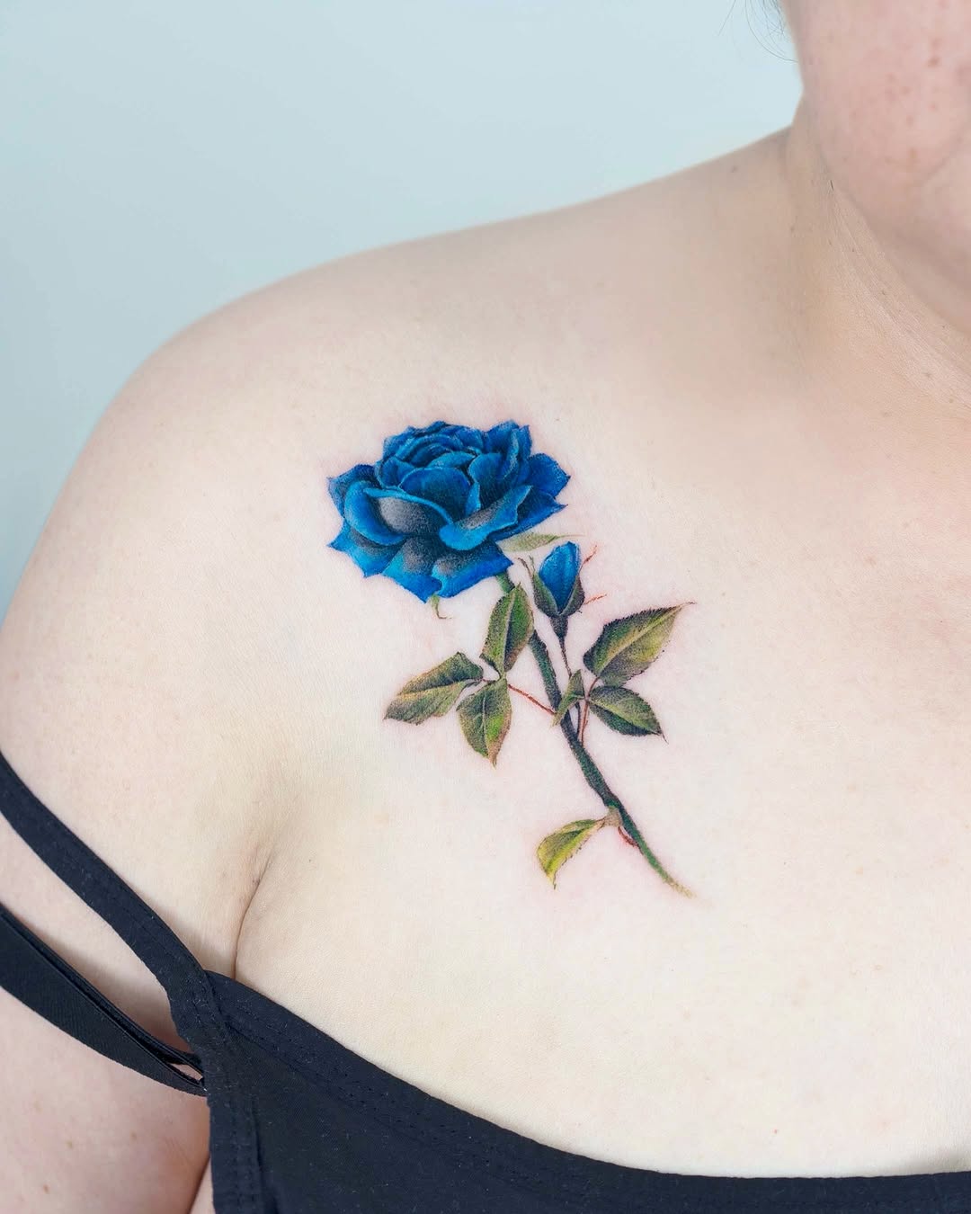 Vibrant blue rose tattoo on shoulder skin
