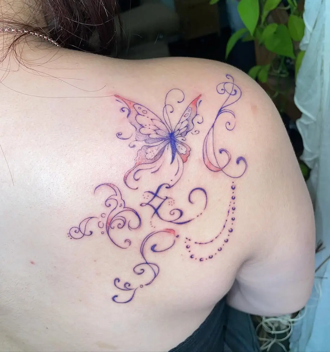 Delicate butterfly tattoo with intricate swirls