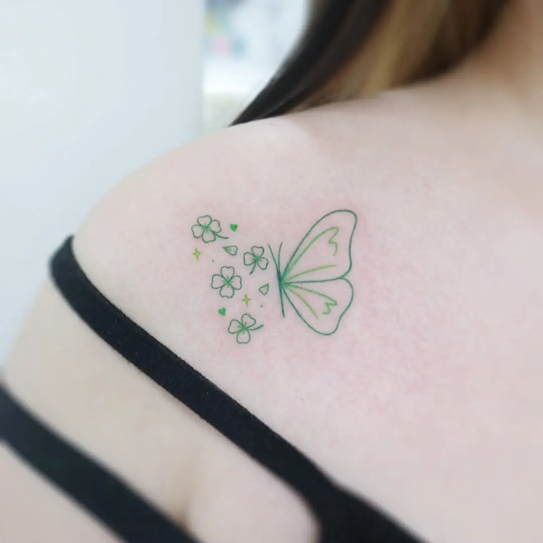 Delicate green butterfly tattoo with floral accents.
