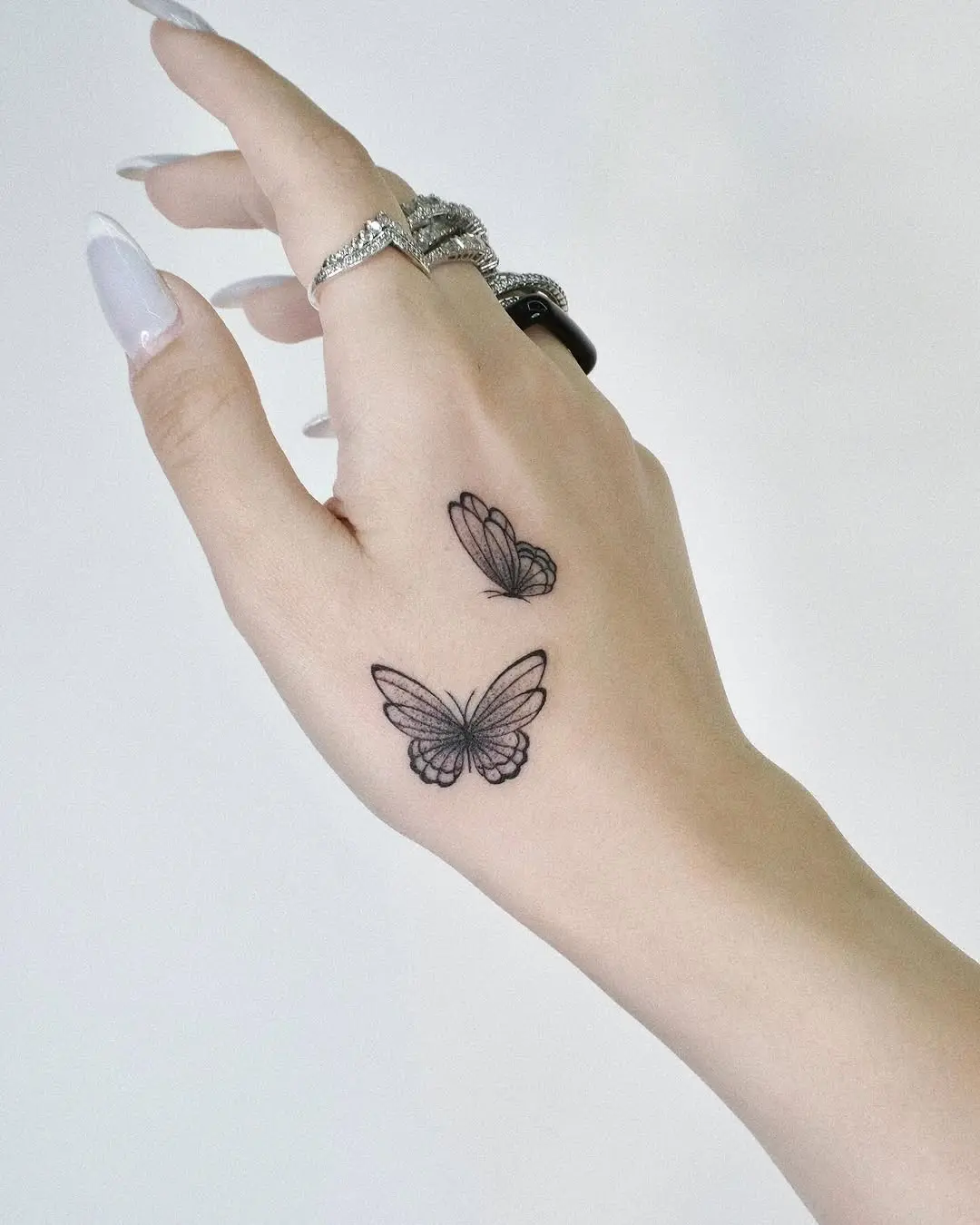 Elegant butterfly tattoos enhancing hand beauty.