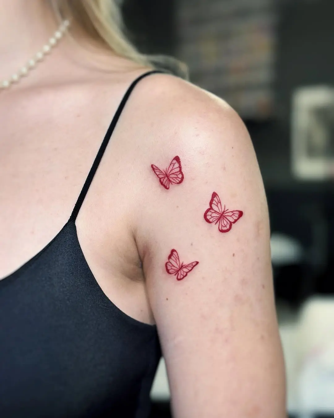 Delicate red butterfly tattoos on the shoulder