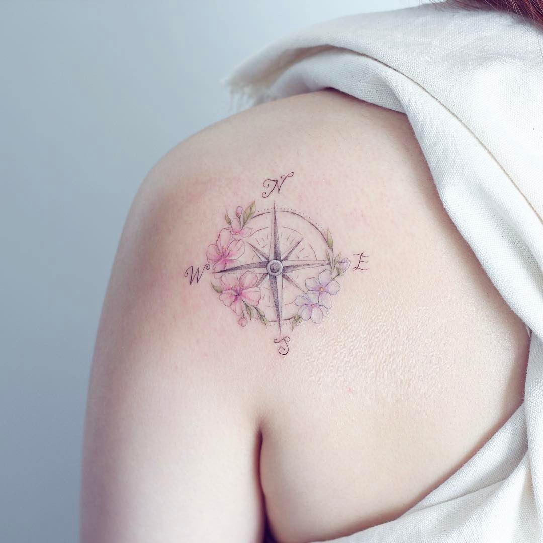 Delicate compass tattoo with floral accents