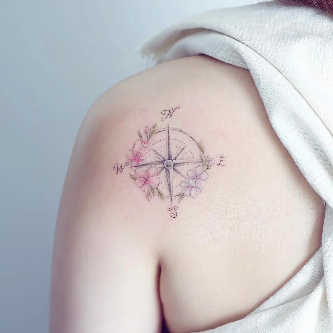 Delicate compass tattoo with floral accents