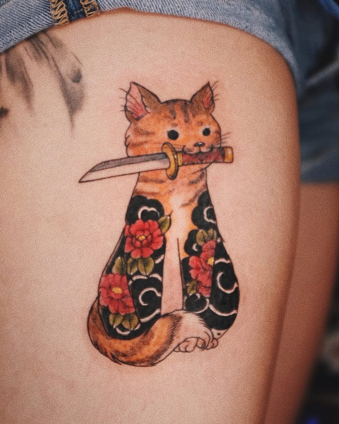 Whimsical cat tattoo with a dagger