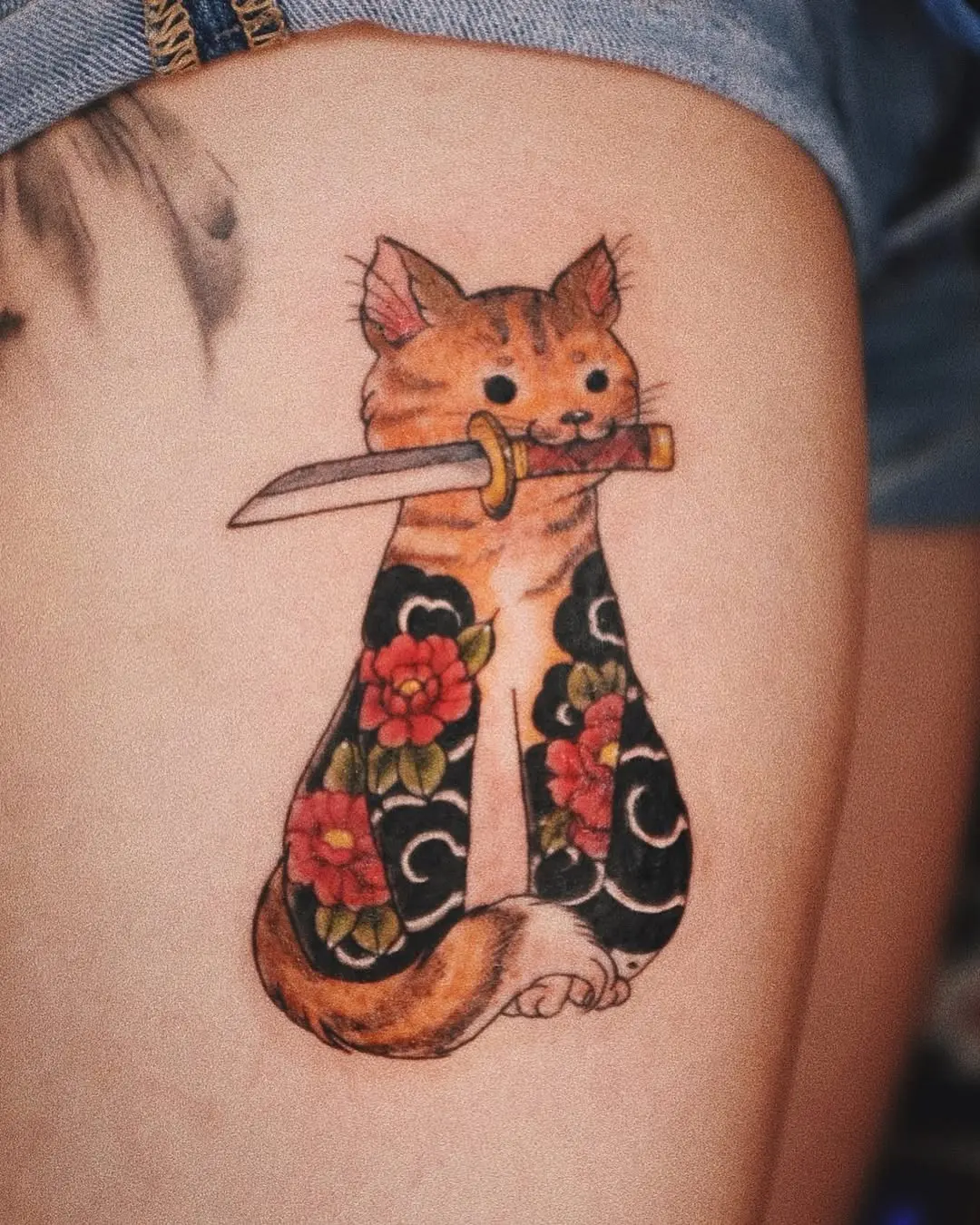 Whimsical cat tattoo with a dagger