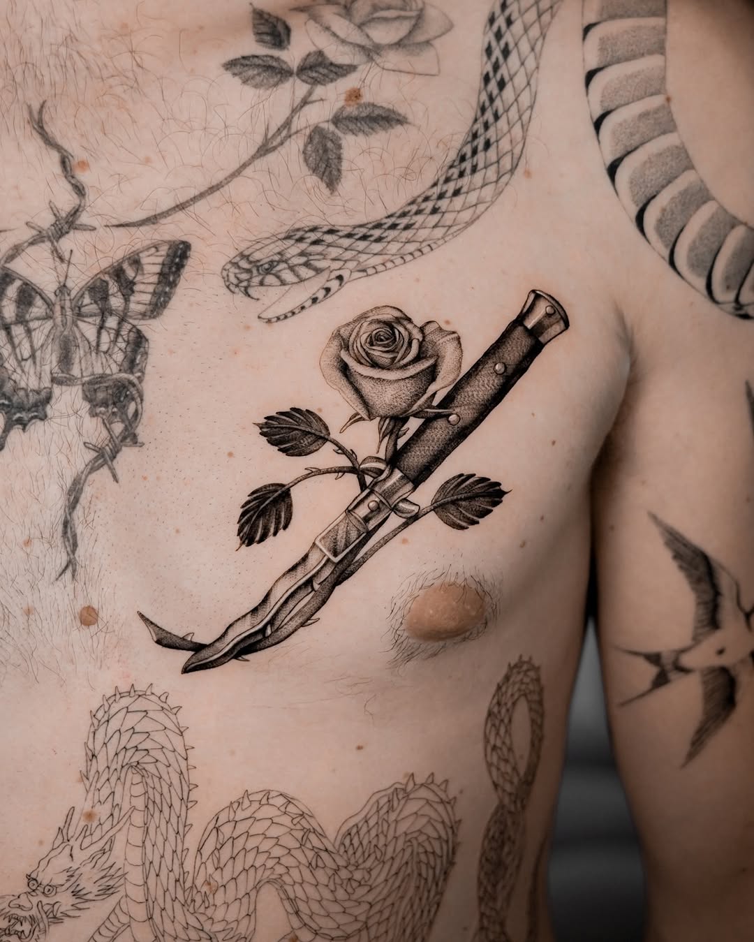 Striking dagger tattoo entwined with a rose