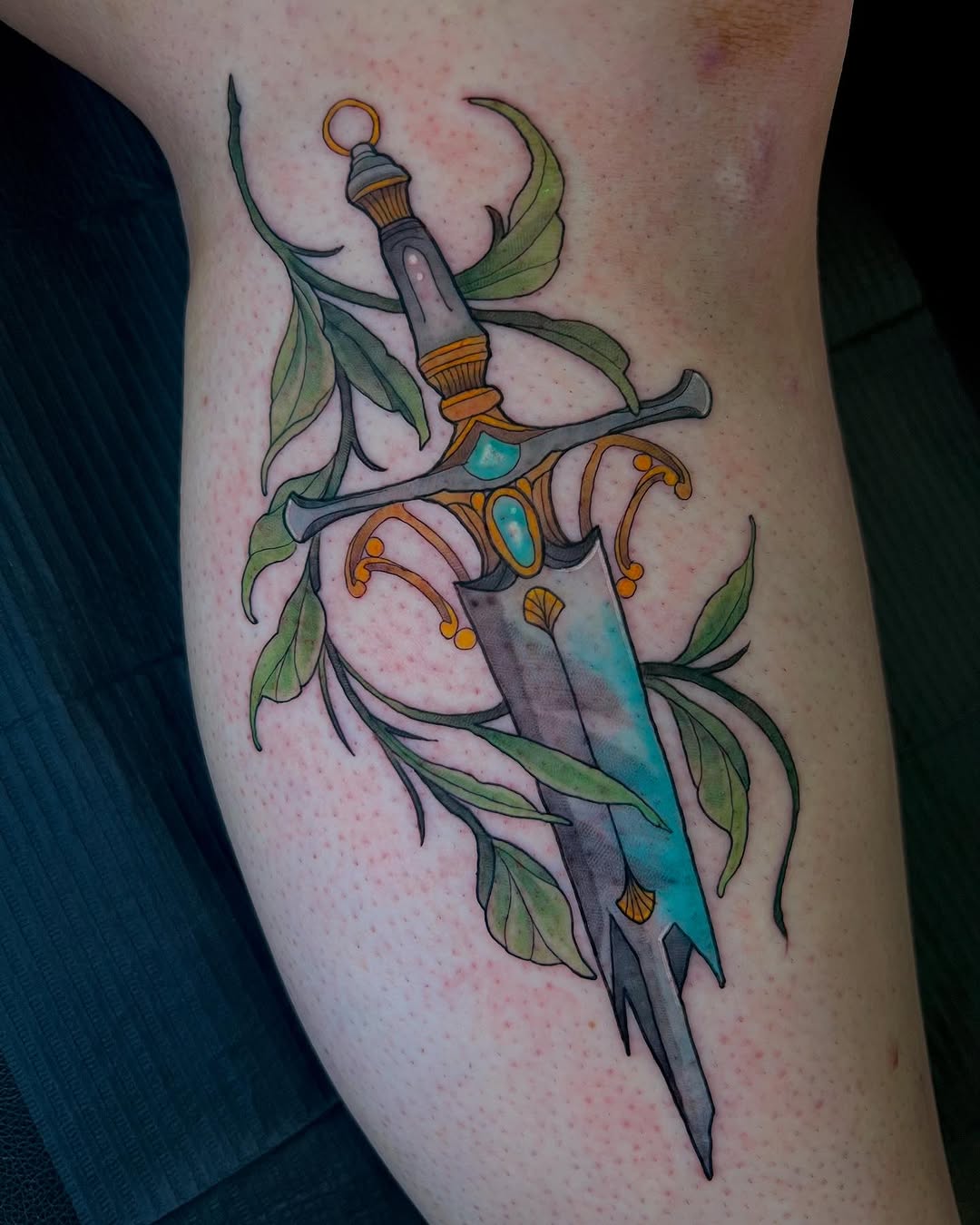 A stunning dagger tattoo with lush leaves