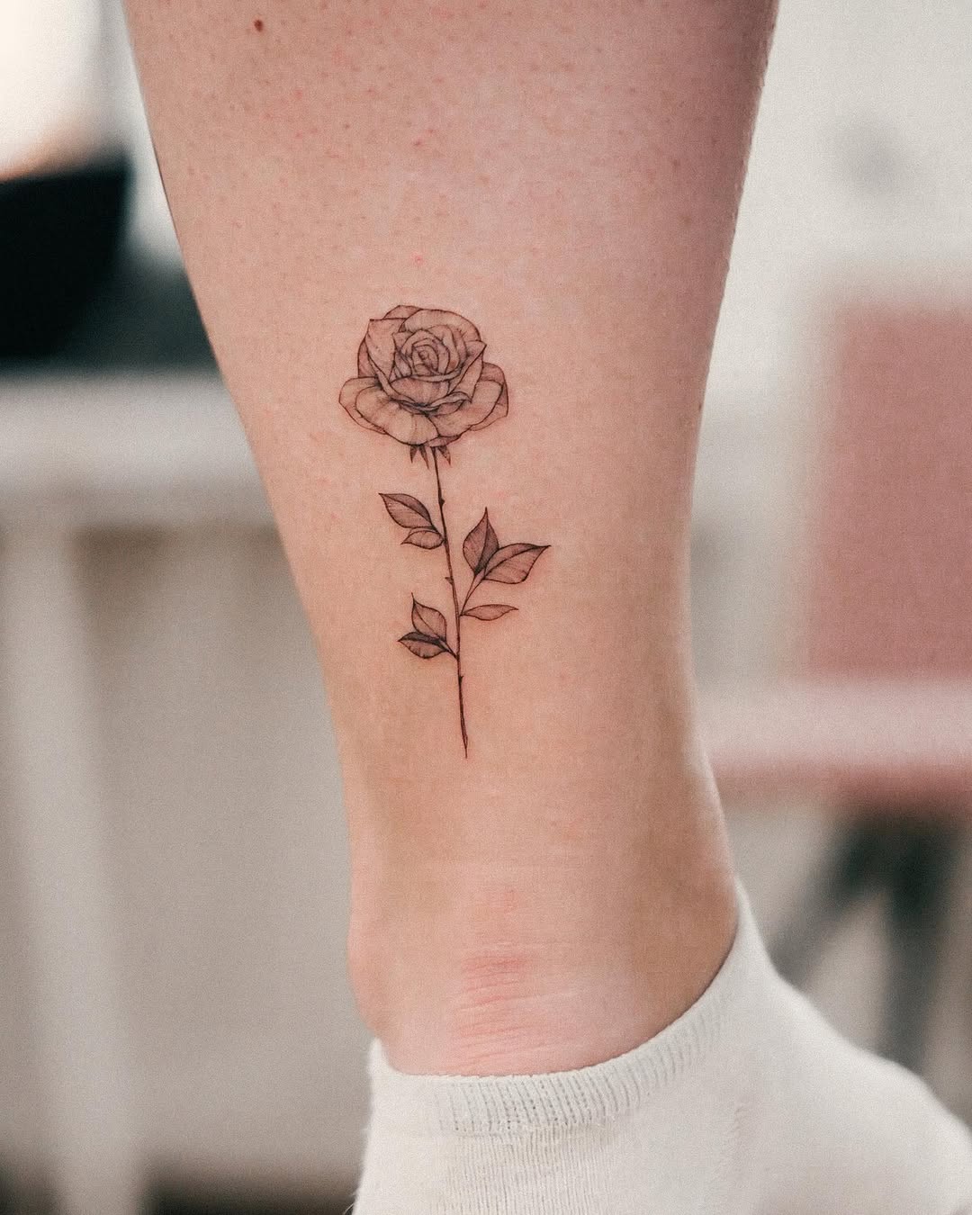 Elegant black line rose tattoo on leg