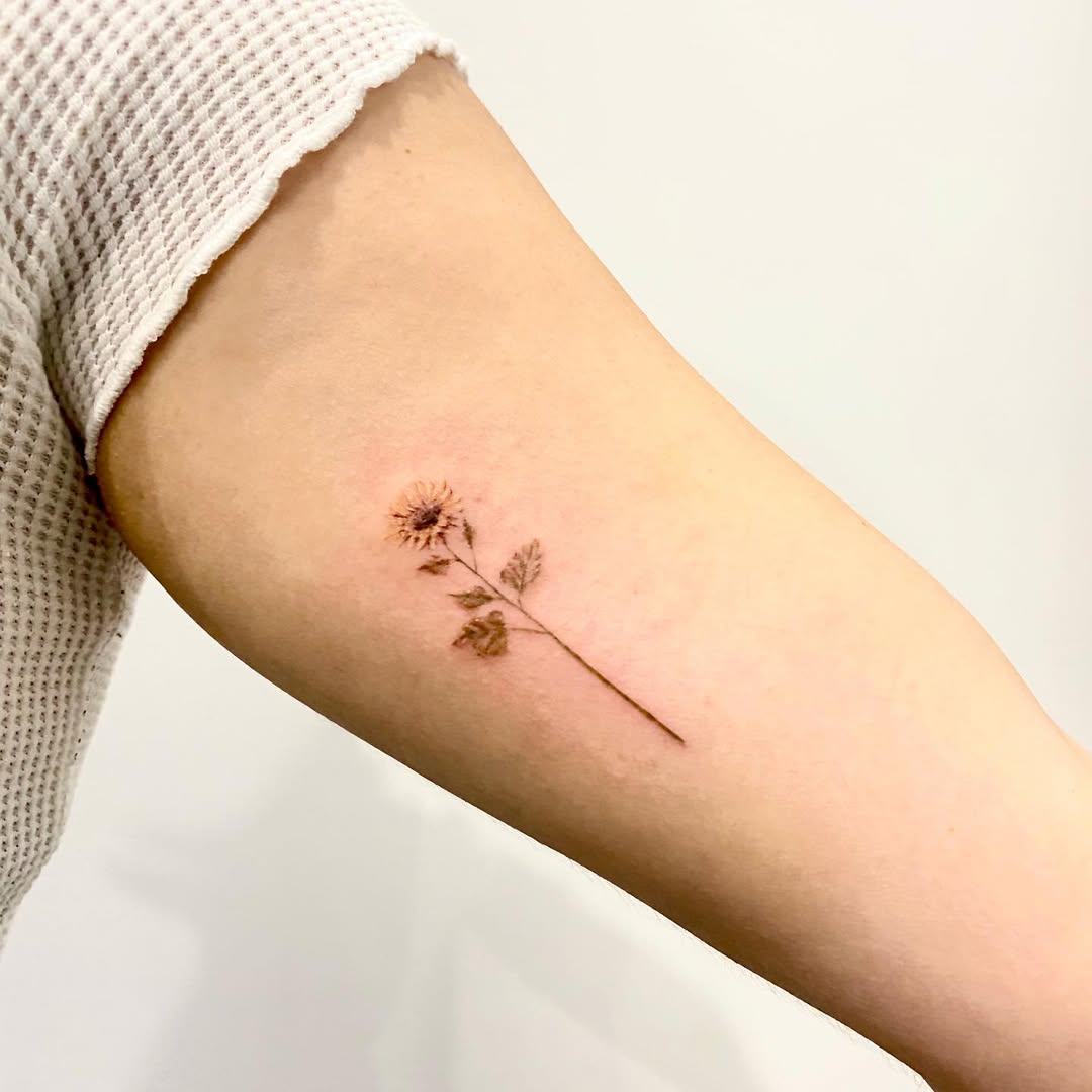 Minimalist sunflower design on a woman's arm