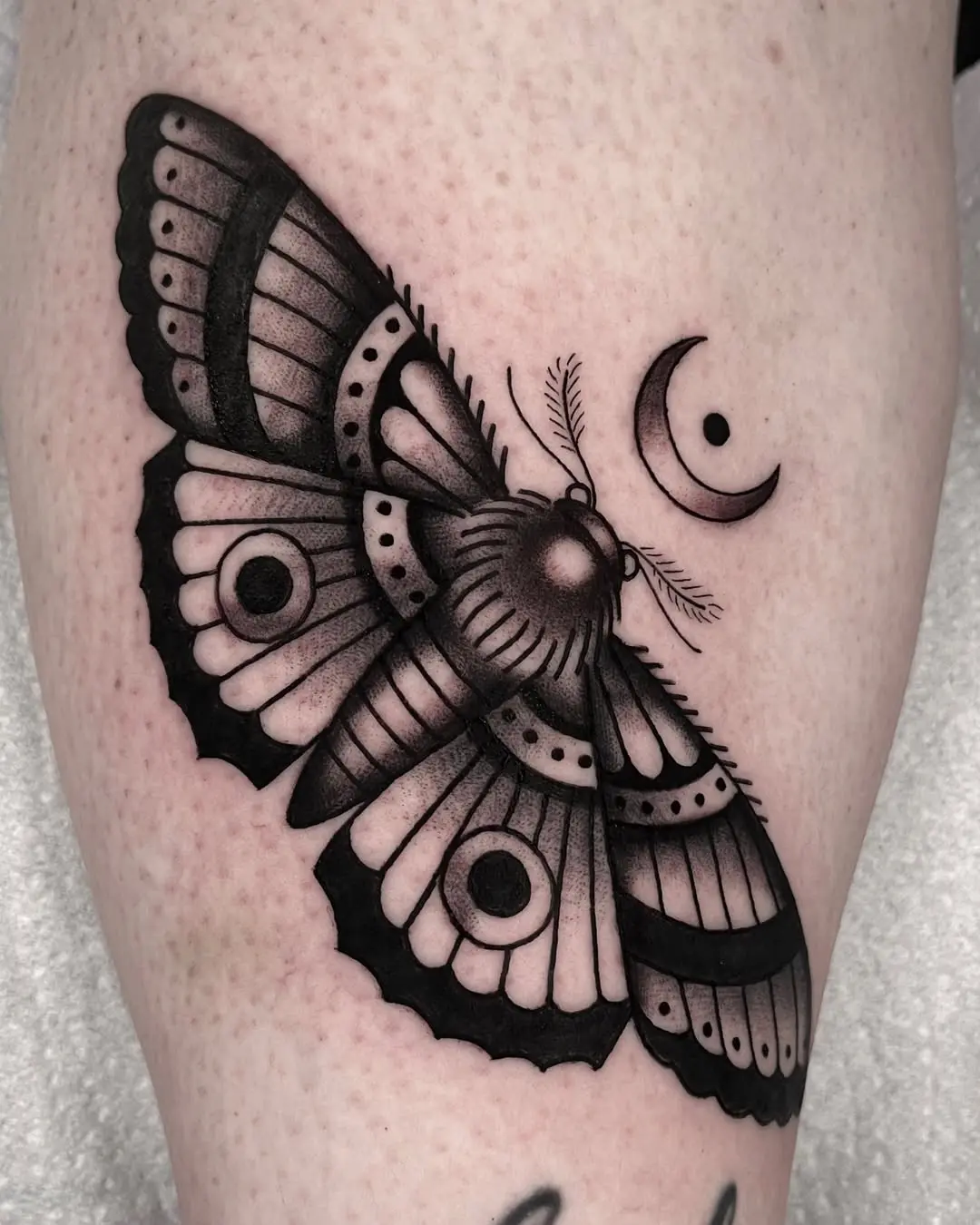 Intricately designed moth tattoo with moon accent
