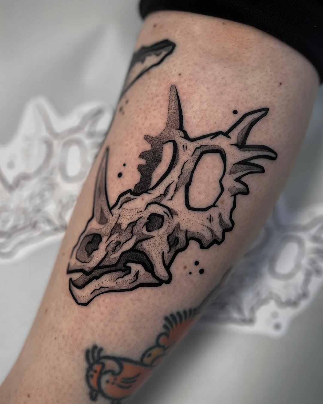 Intricate dinosaur skull tattoo in black ink