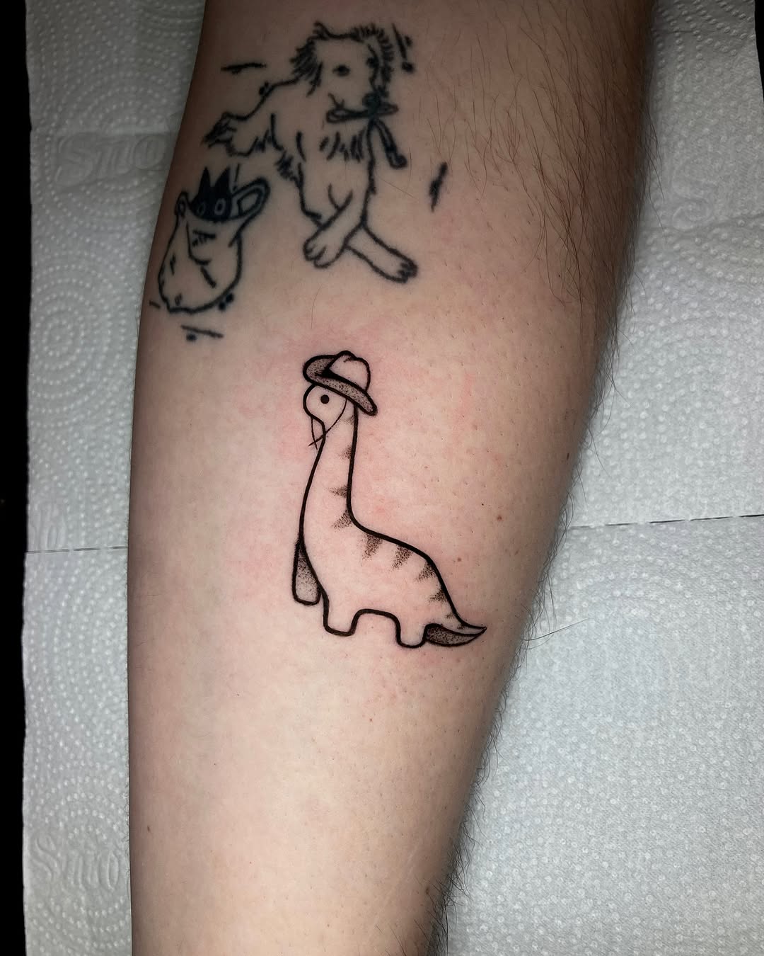 Whimsical dinosaur tattoo with hat design