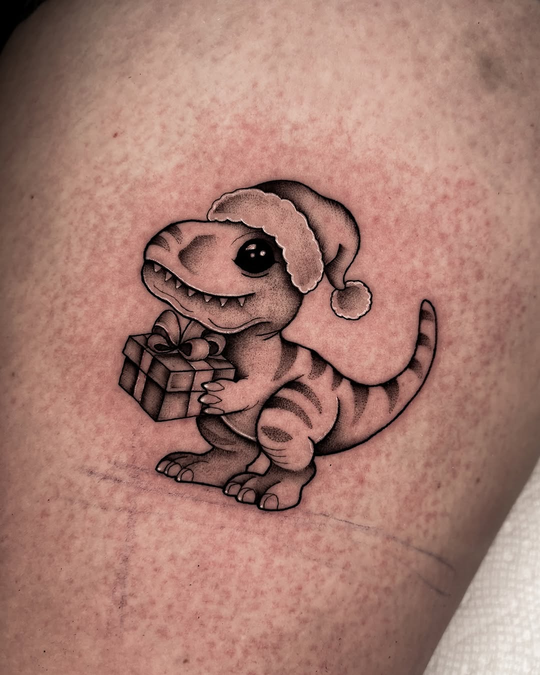 Festive dinosaur tattoo with holiday cheer