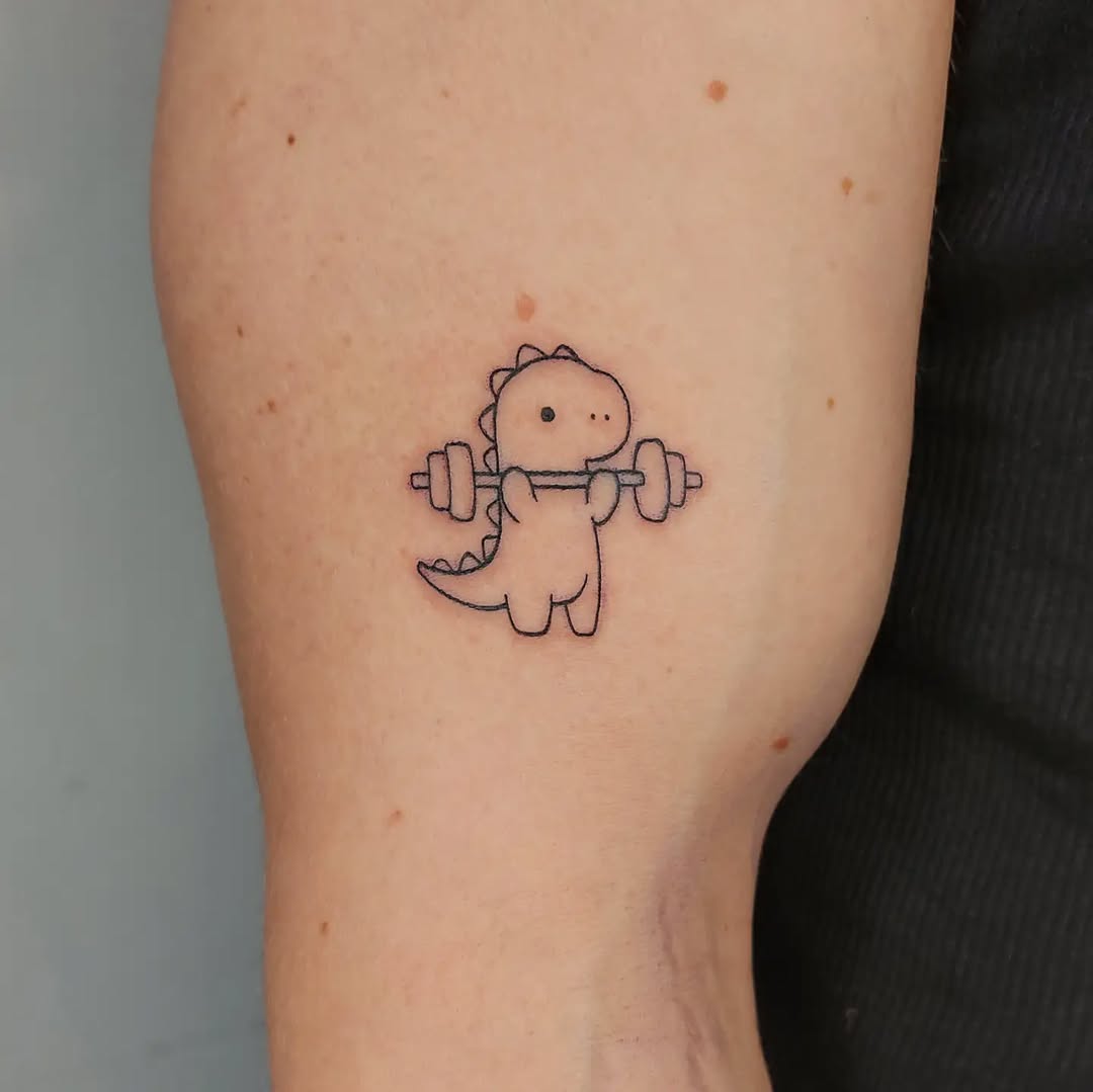 Adorable dinosaur lifting weights tattoo