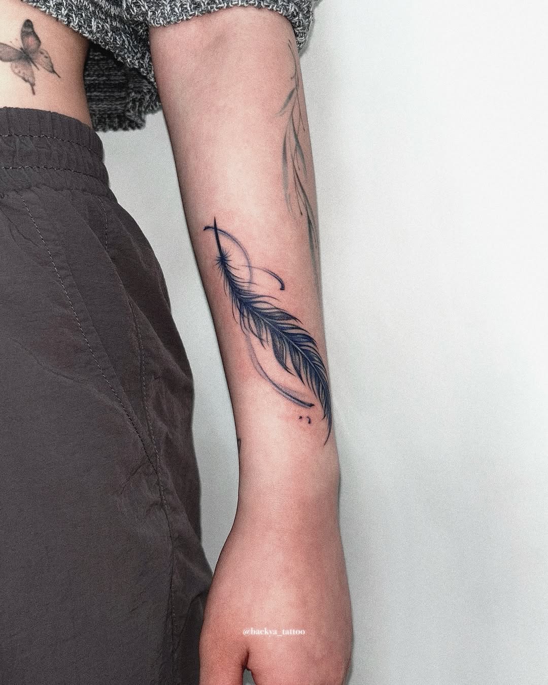 A striking feather tattoo on the forearm