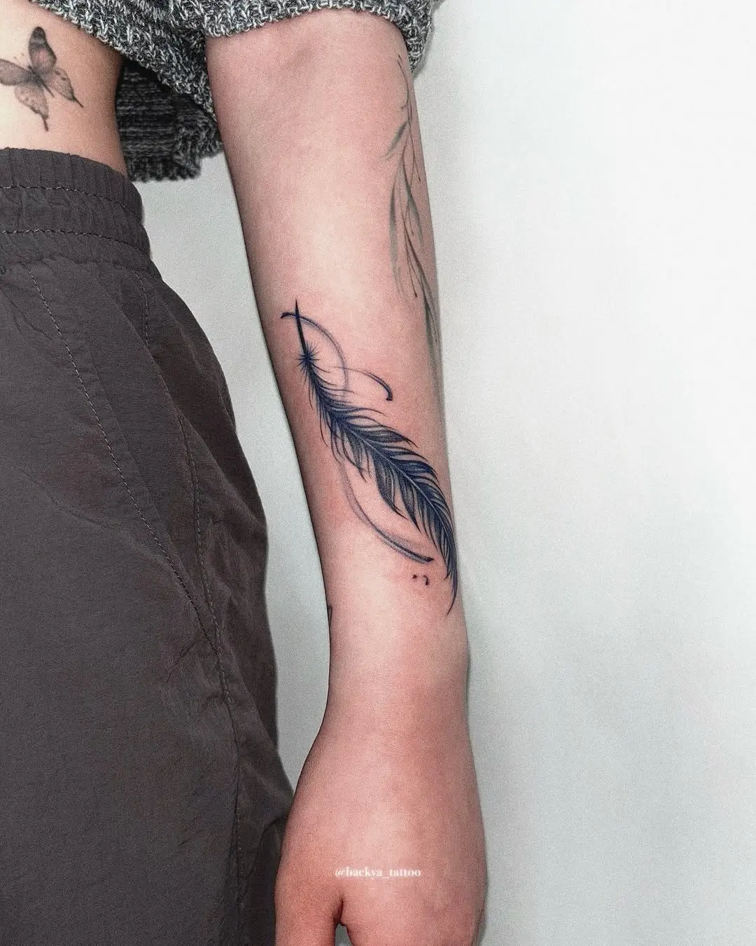 A striking feather tattoo on the forearm