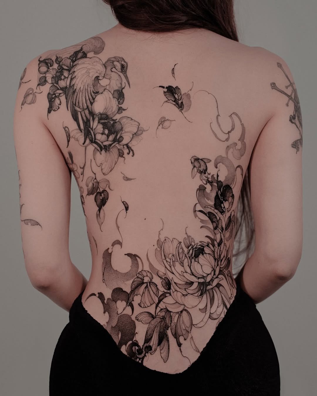 Elegant floral back tattoo for women.