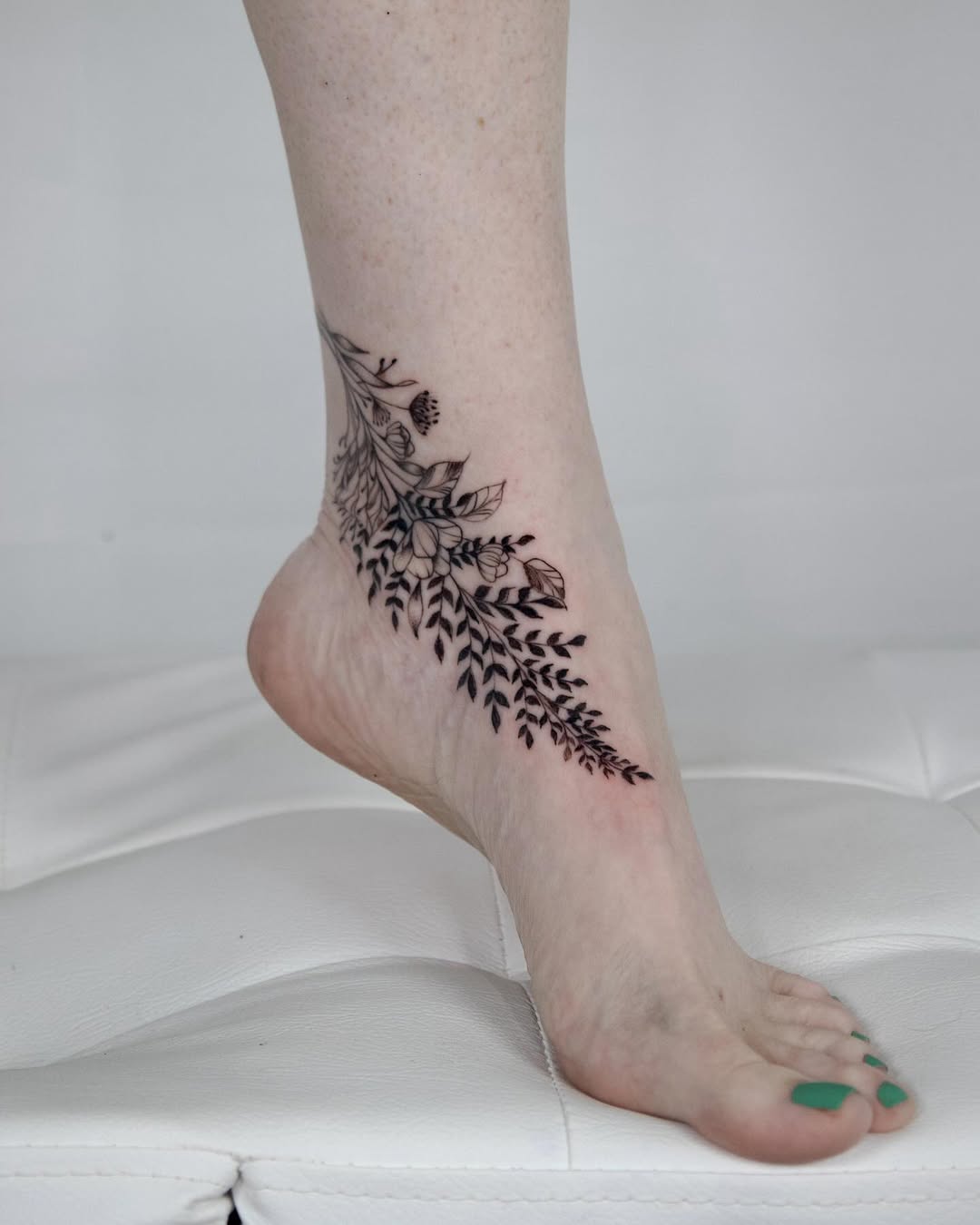 Elegant floral foot tattoo wrapped around ankle