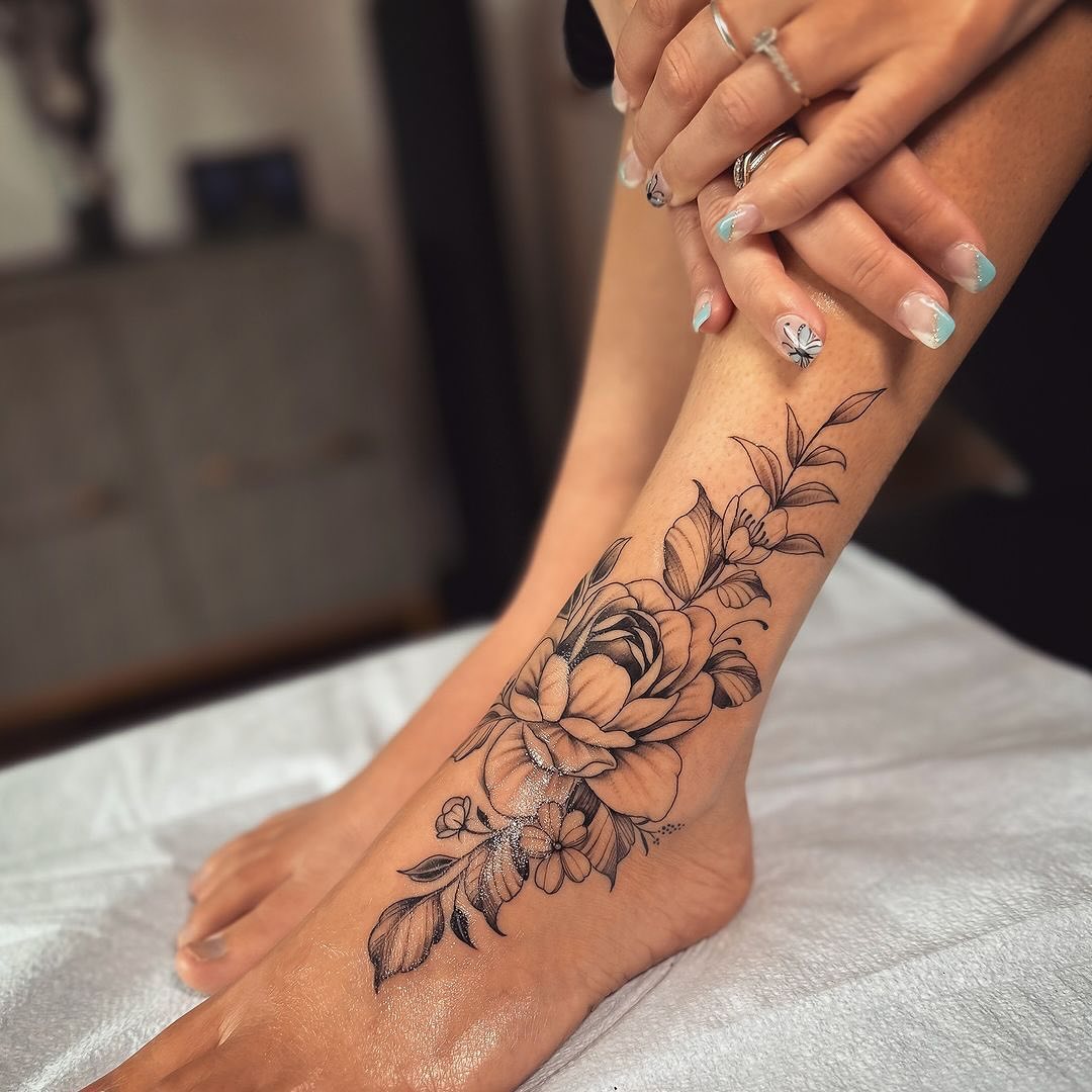 Elegant floral foot tattoo in black ink