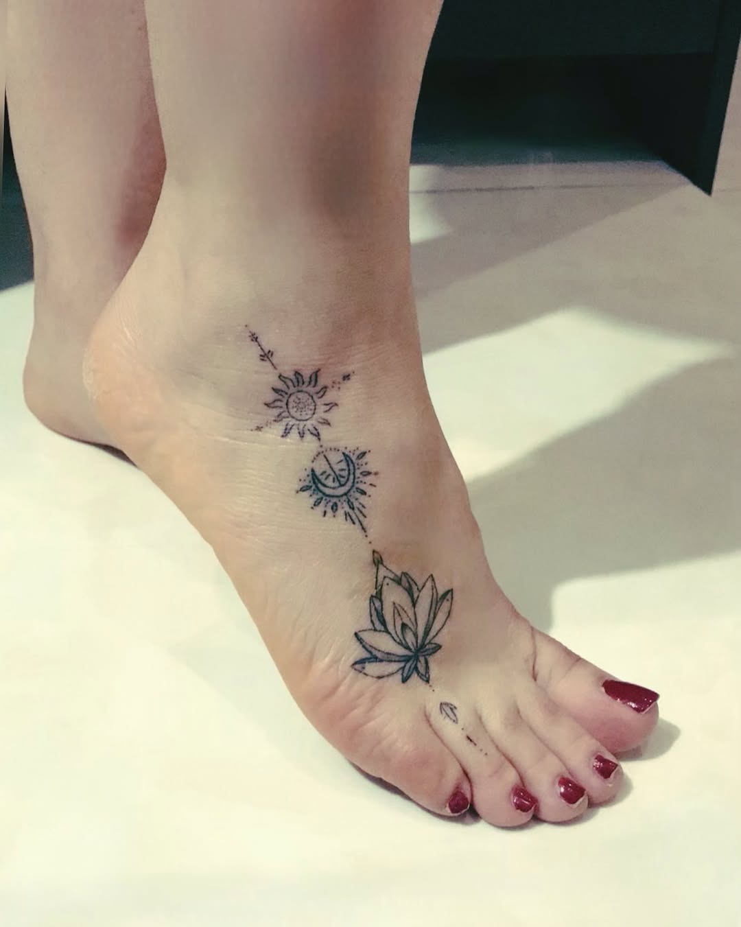 Intricate foot tattoo showcasing sun and lotus