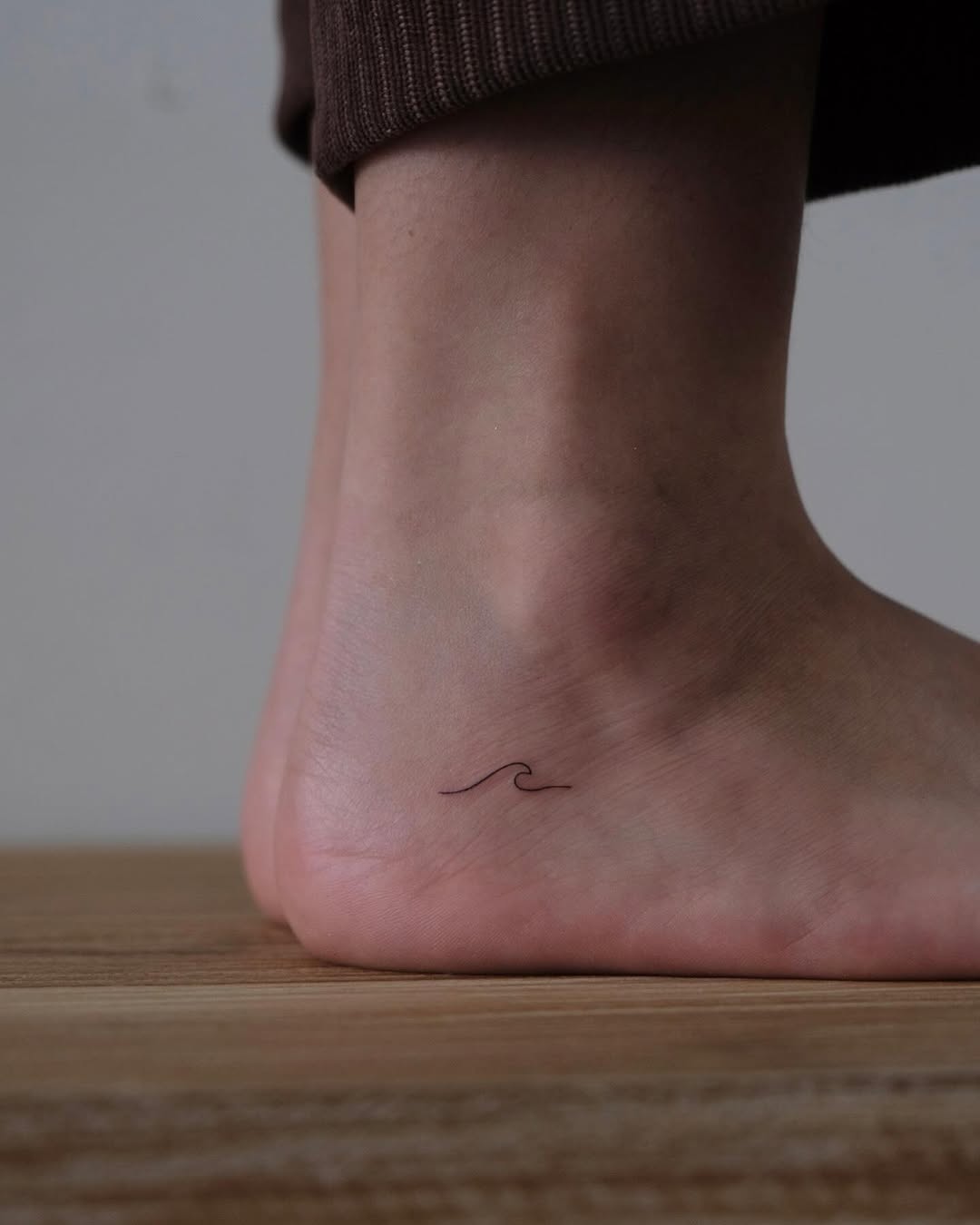 Minimalist wave tattoo on the ankle