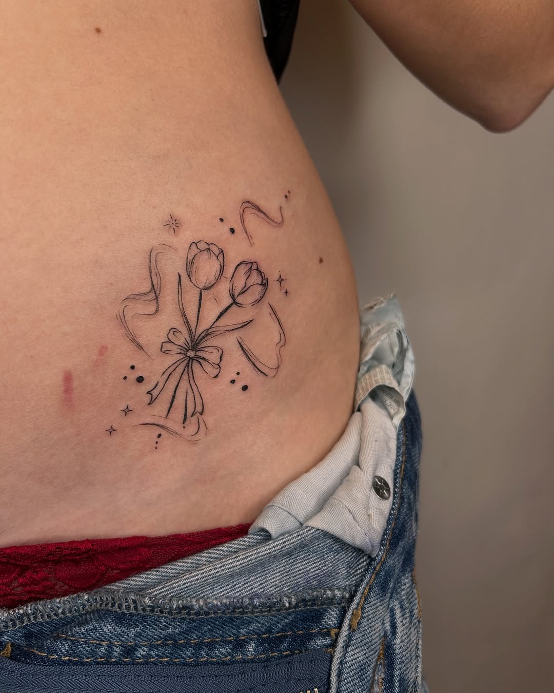 Elegant floral hip tattoo with delicate bow