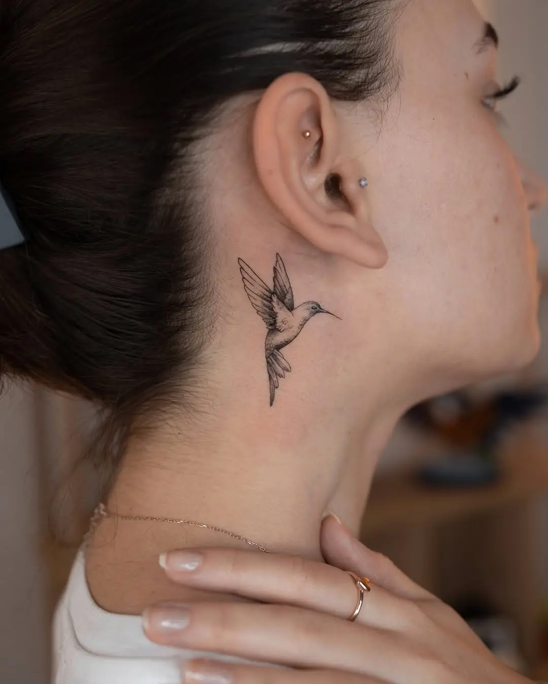 Delicate hummingbird tattoo on the neck