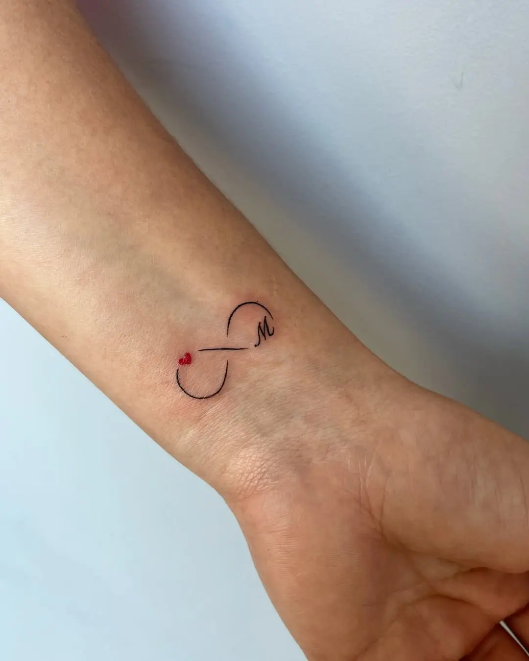 Minimalistic infinity tattoo with heart accent