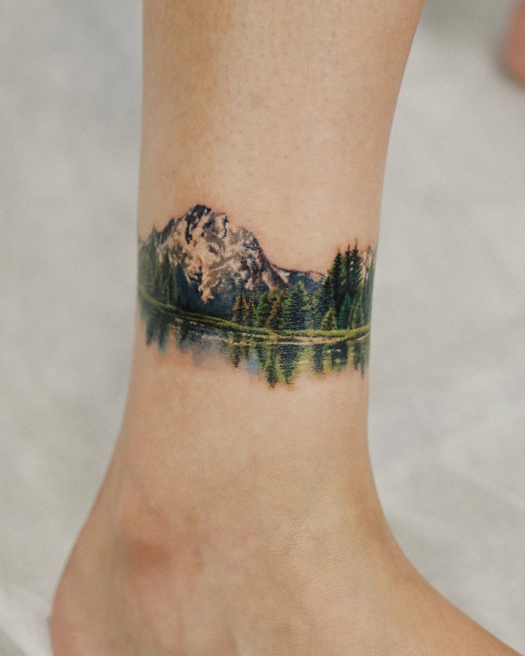 Stunning ankle tattoo with mountain reflection