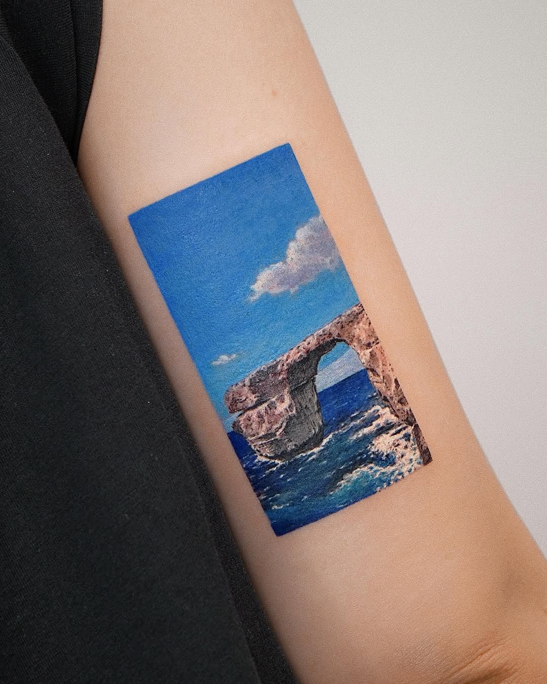 Vibrant ocean archway tattoo on arm