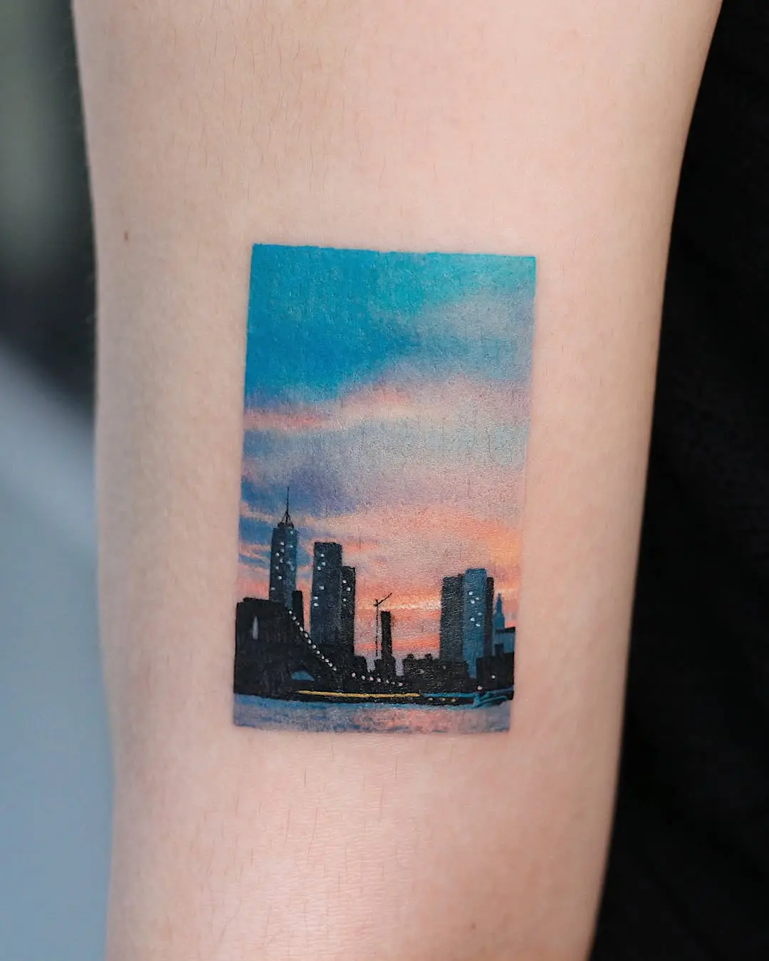 Vibrant cityscape tattoo captures a stunning sunset