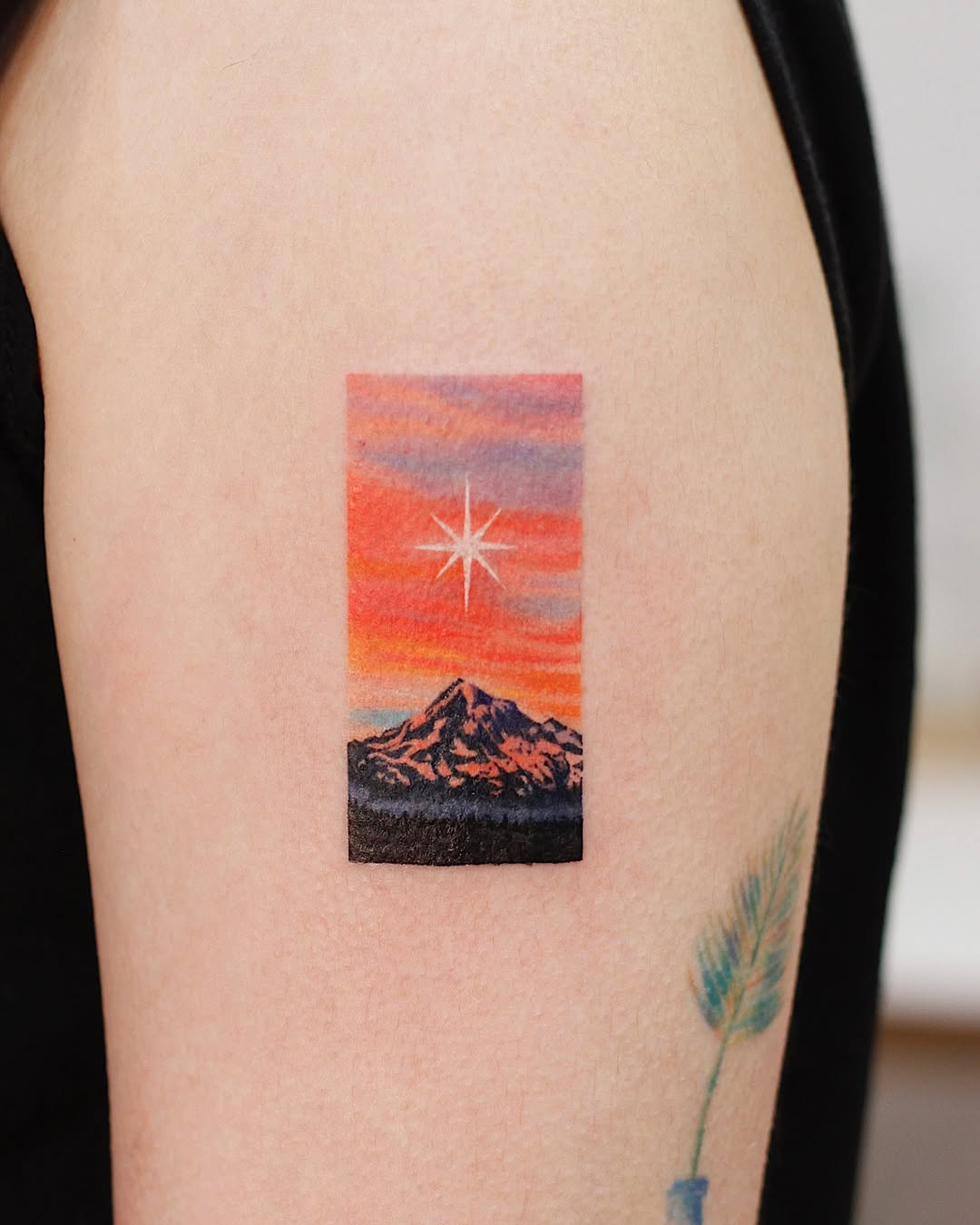 Vibrant sunset mountain tattoo with star detail