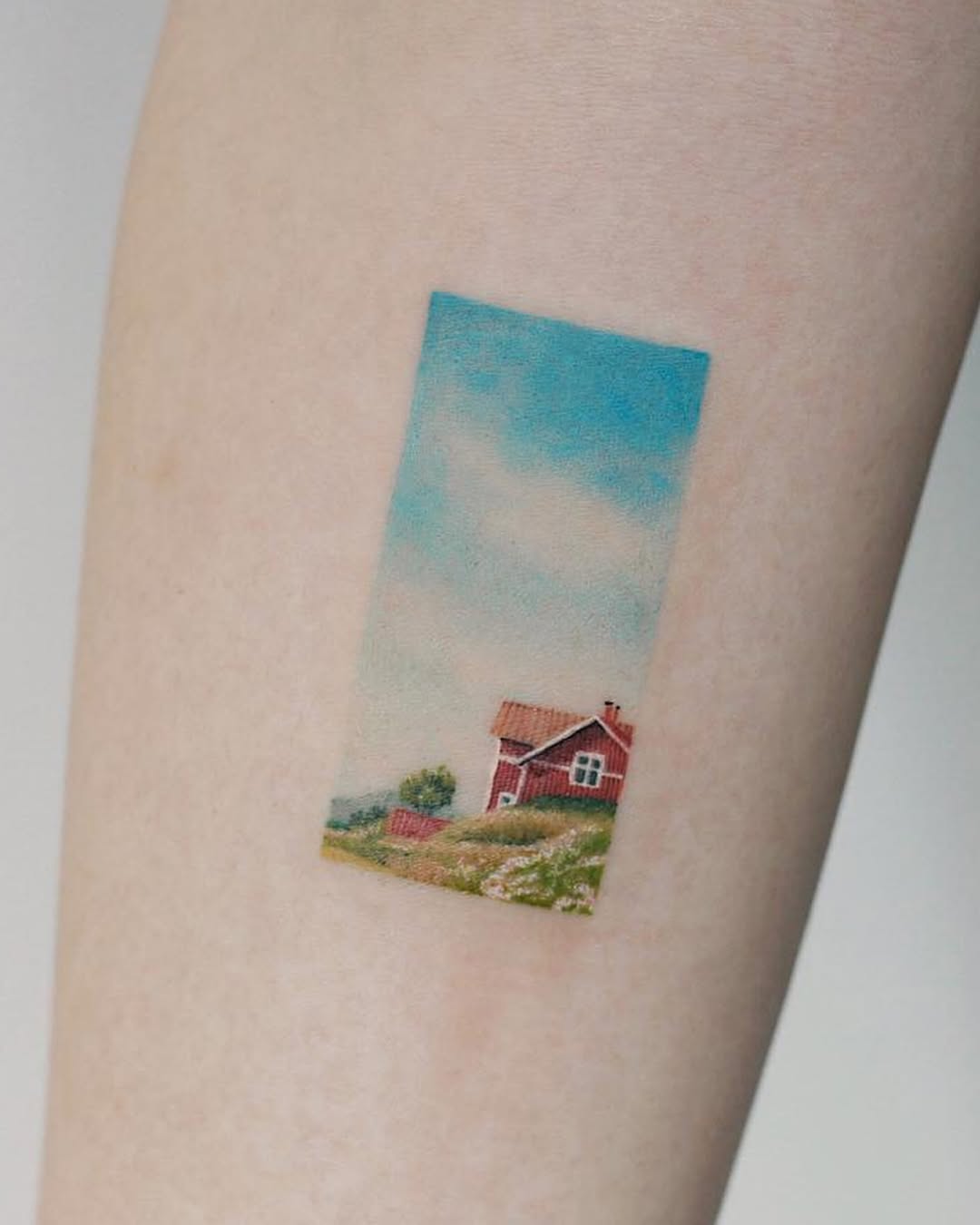 Charming countryside landscape tattoo on arm