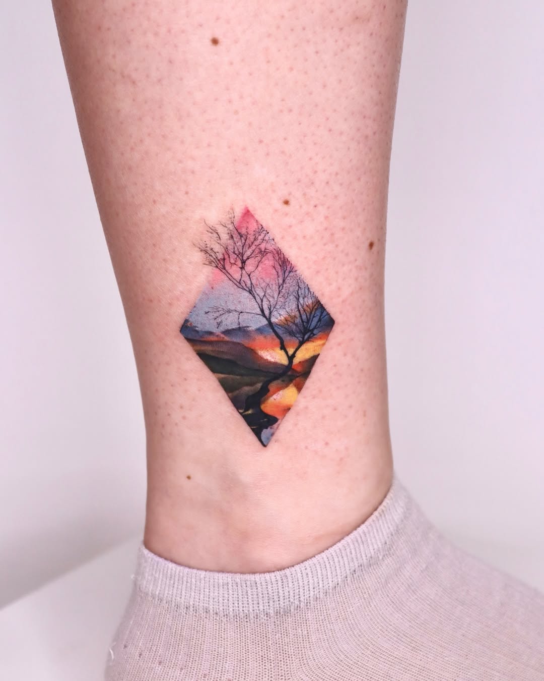 Stunning diamond-shaped sunset landscape tattoo