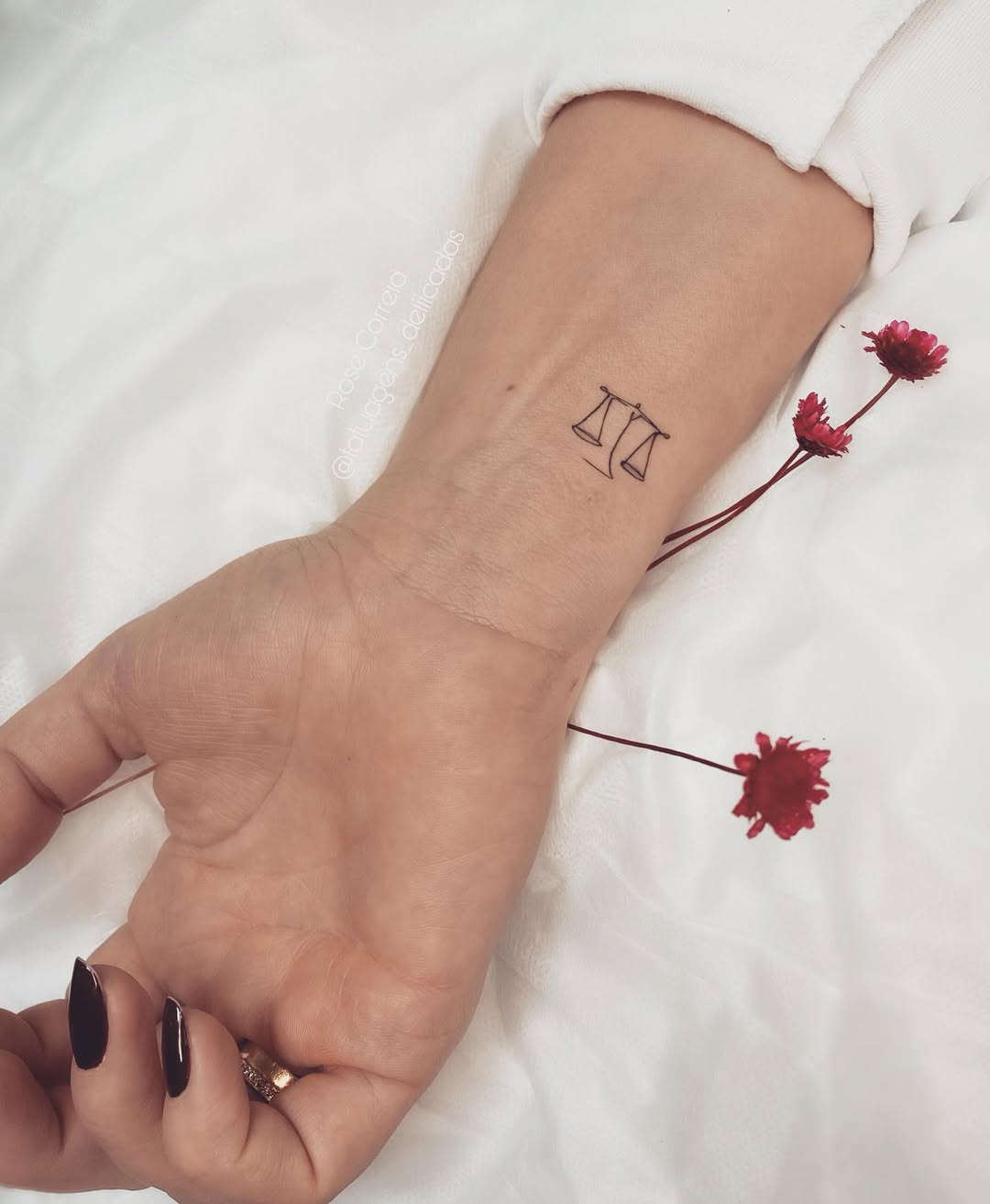 Minimalist Libra scale tattoo on wrist