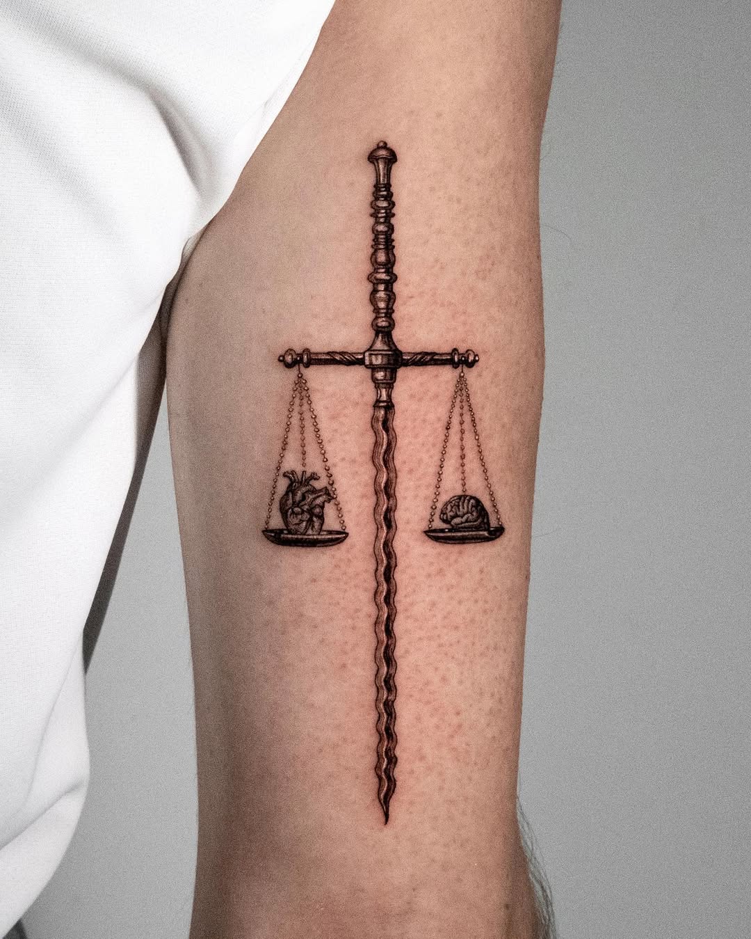 Elegant Libra scales tattoo with sword design.