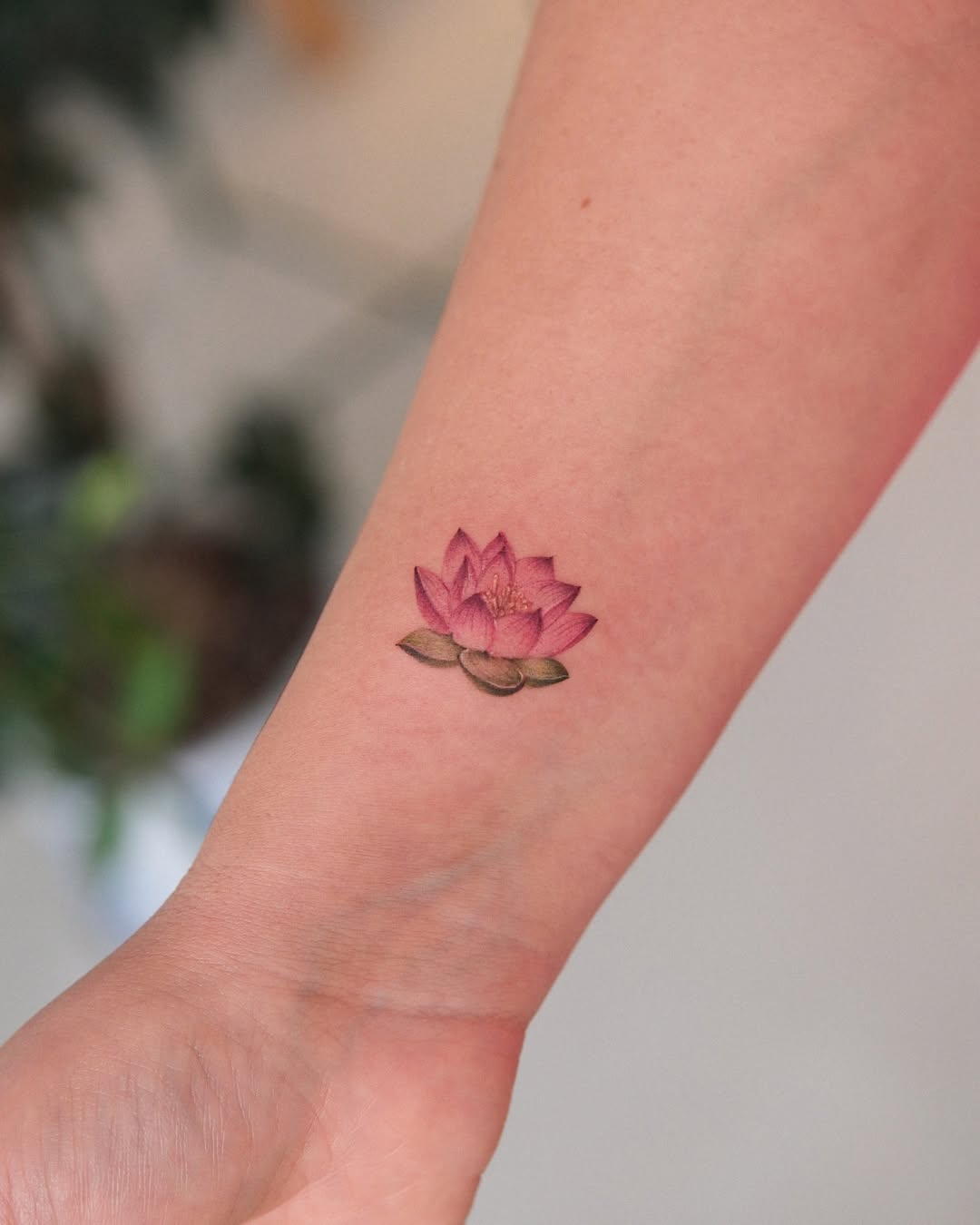 Vibrant pink lotus tattoo on the arm