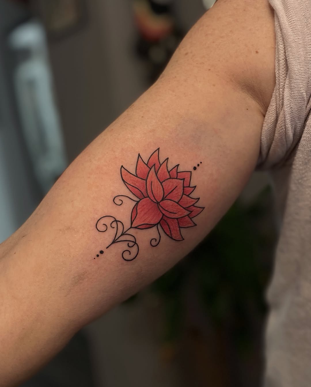 Elegant red lotus tattoo on inner bicep