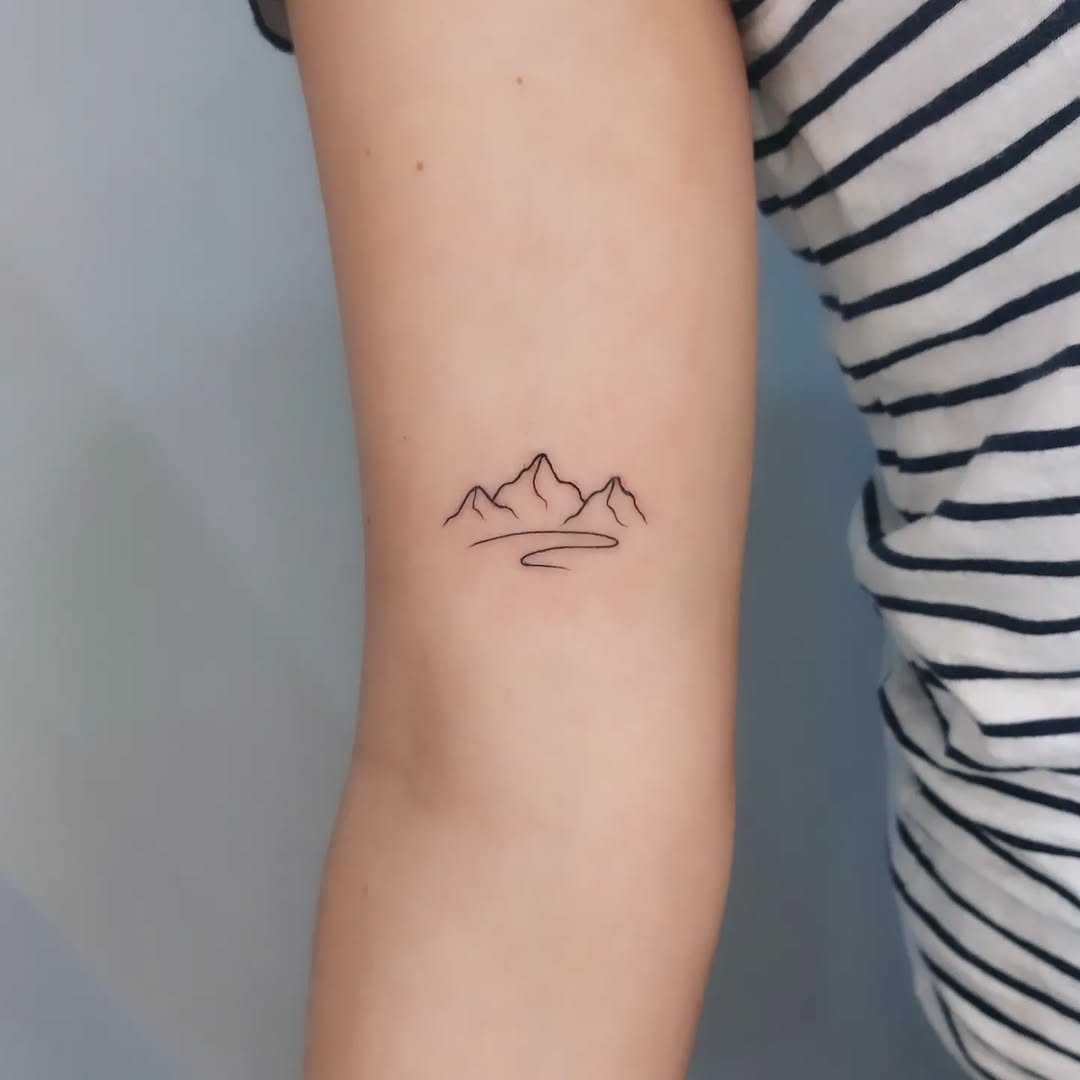 Minimalistic mountain outline tattoo on arm