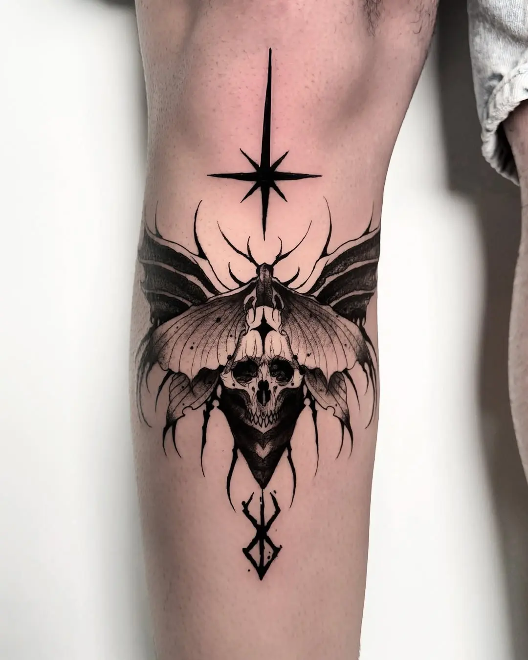 Intricate moth tattoo with striking skull design