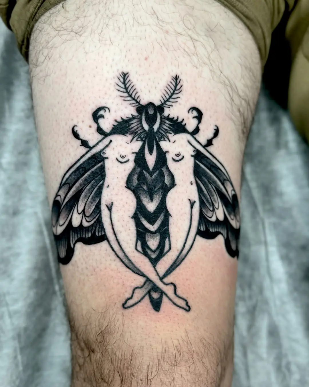 Intricate black moth tattoo with floral elements