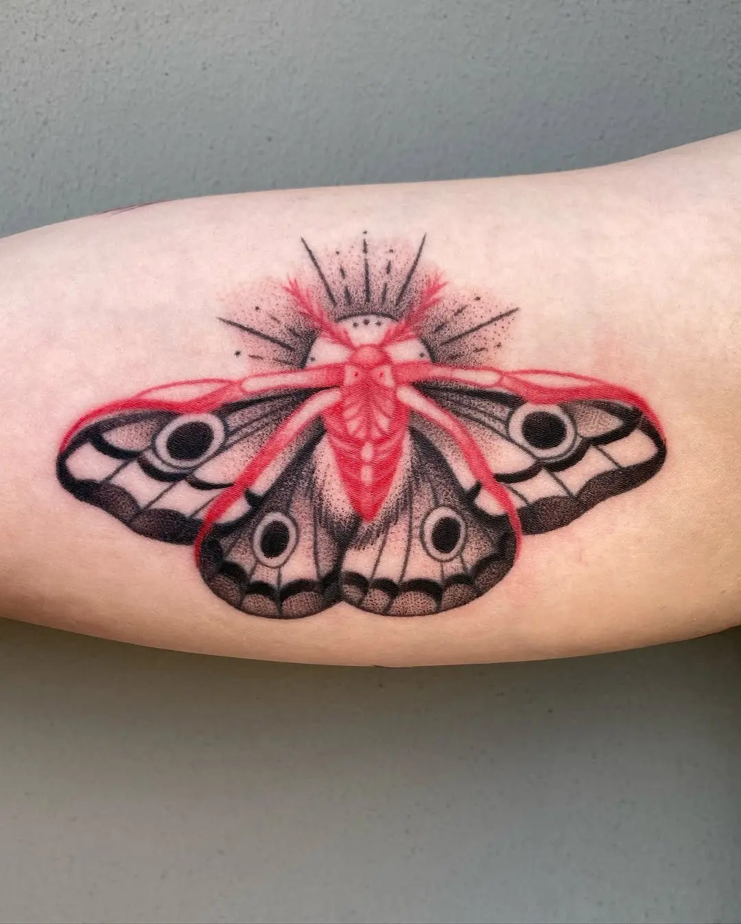 Intricate moth tattoo with striking red accents