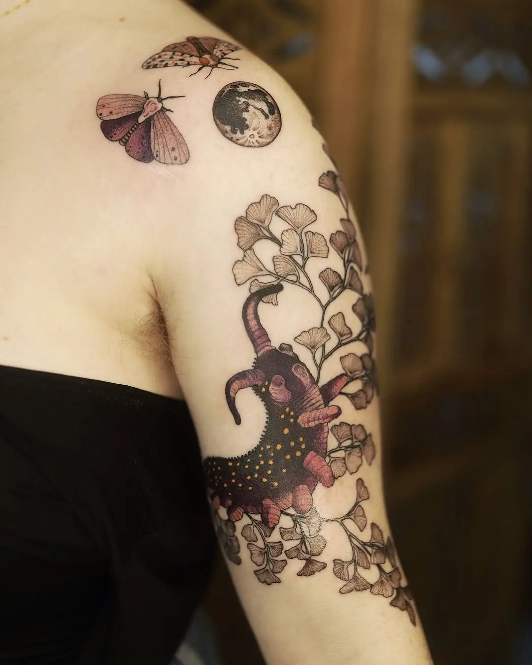 Intricate moth tattoo with floral elements and moon.