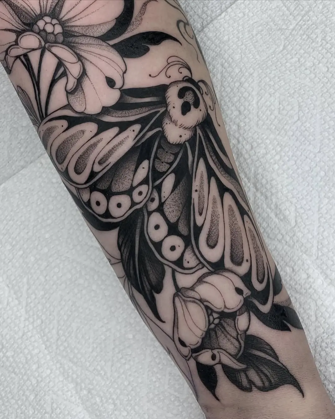 Intricate moth tattoo with floral elements
