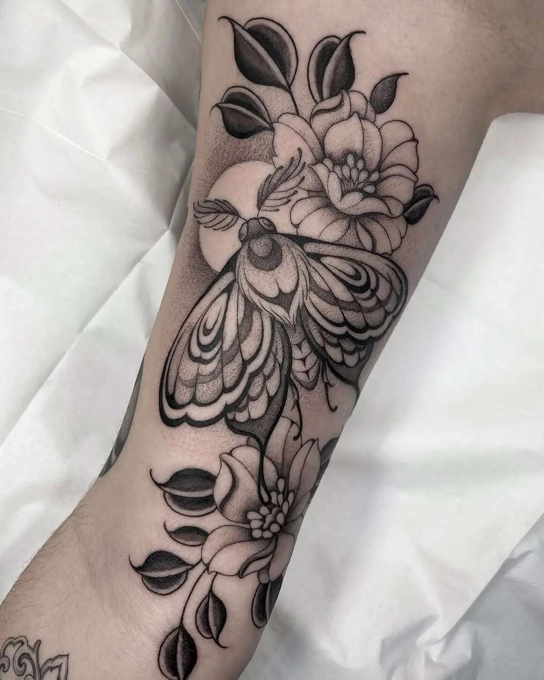 Elegant moth tattoo surrounded by blooming flowers
