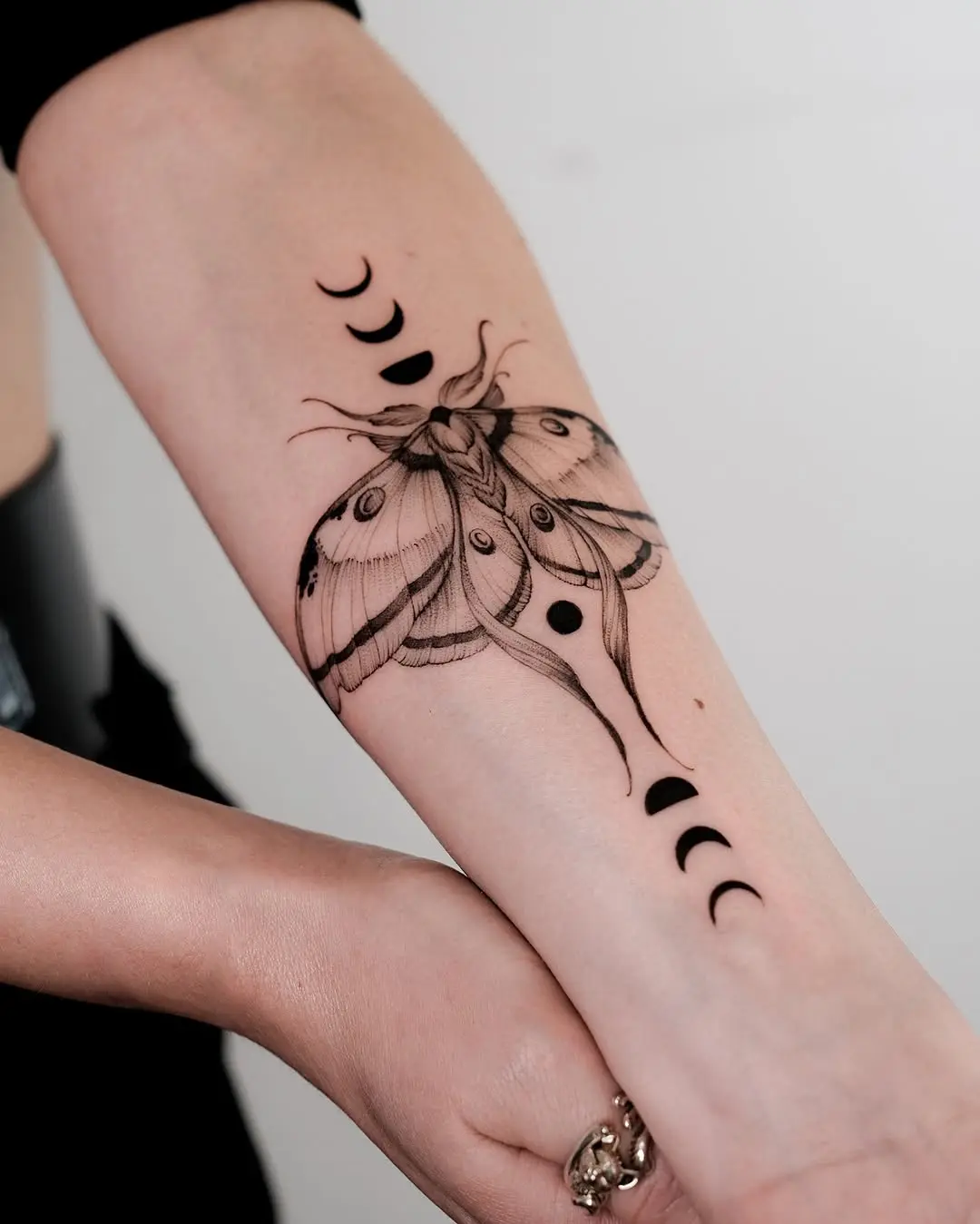 Elegant moth tattoo with moon phase motifs