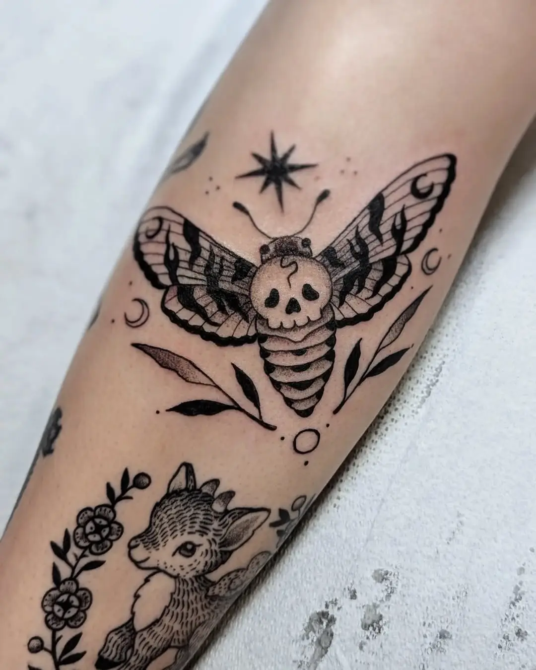Intricate skull moth tattoo design with foliage