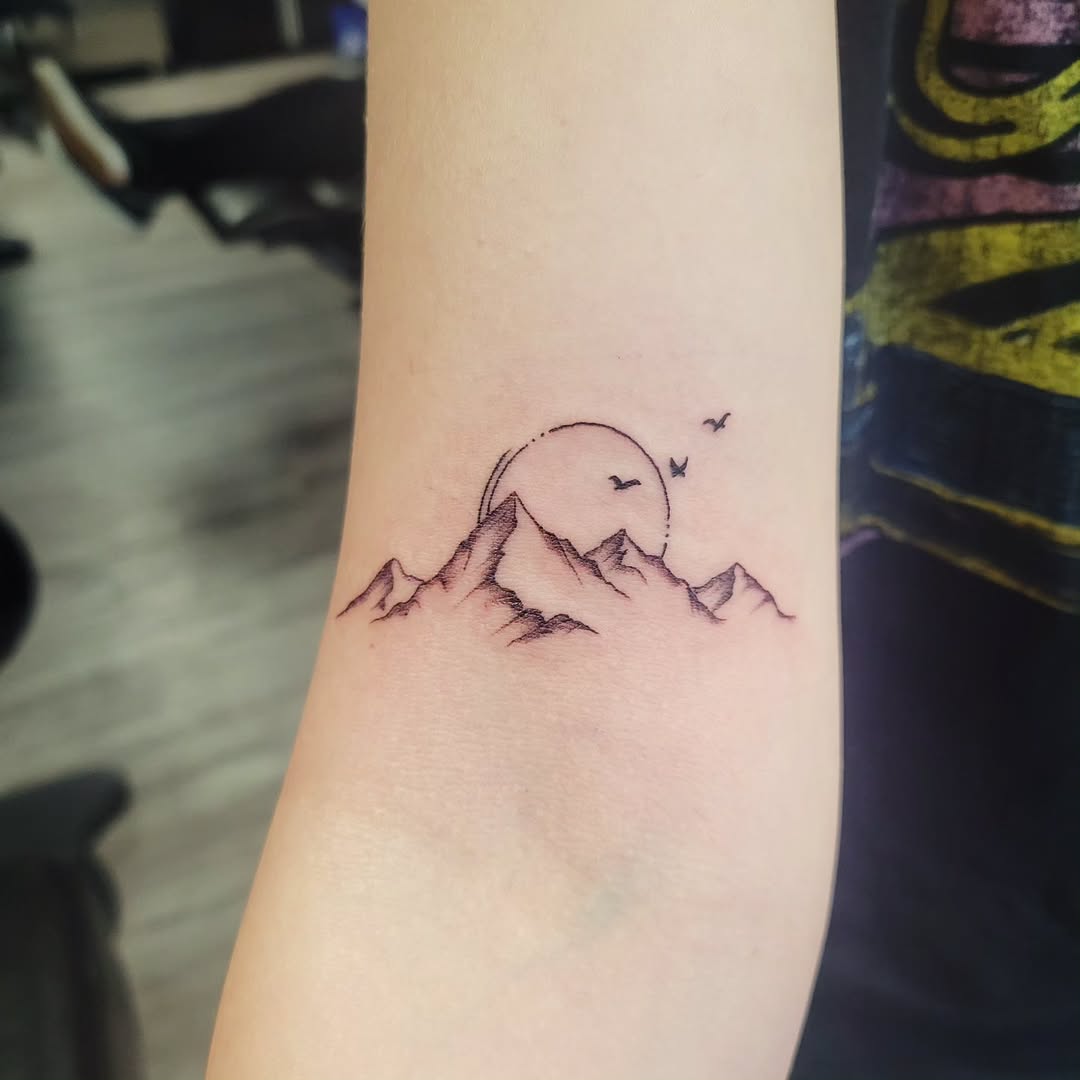 Minimalist mountain tattoo with sunset vibes